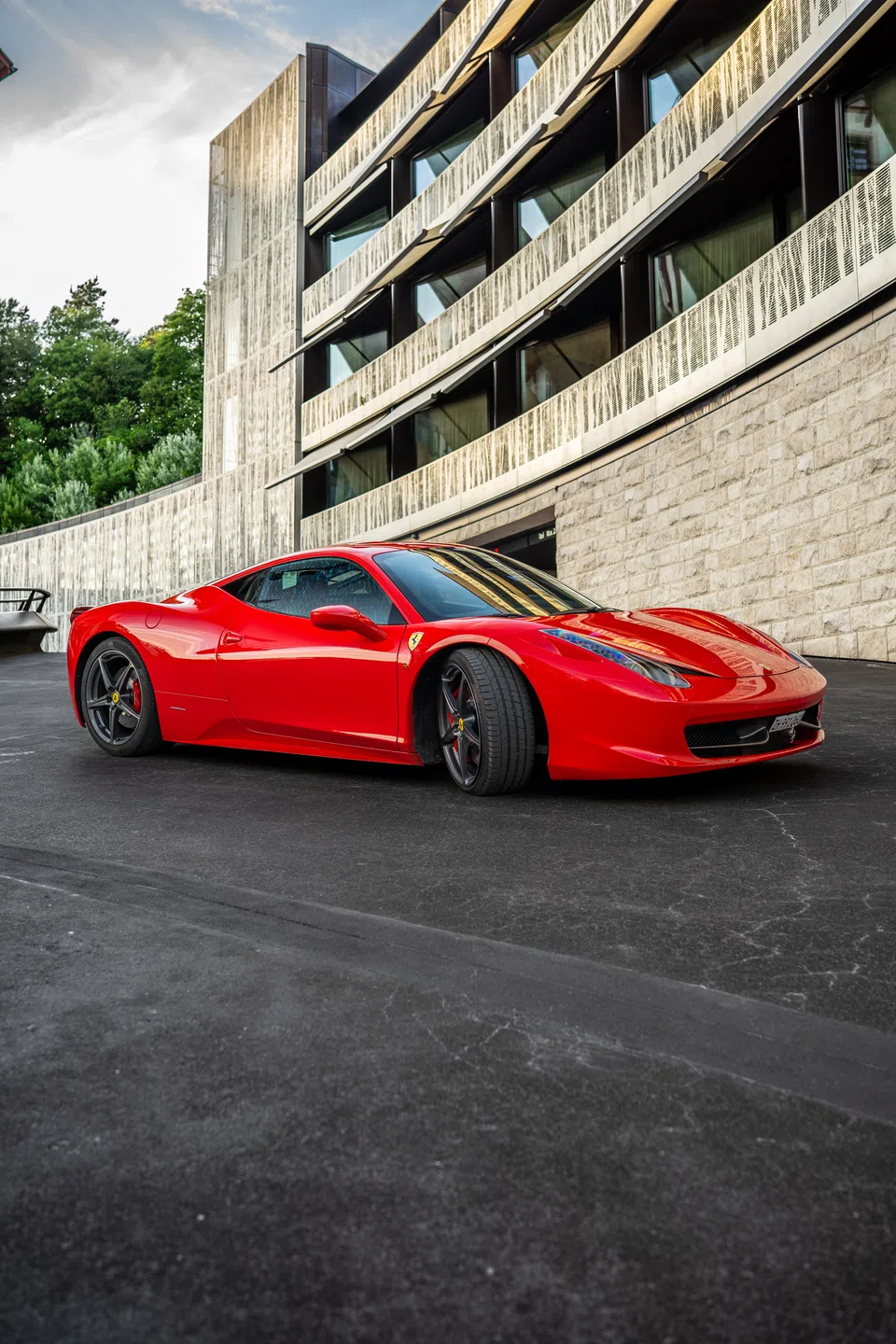 Ferrari 458 Italia beside a contemporary hotel façade