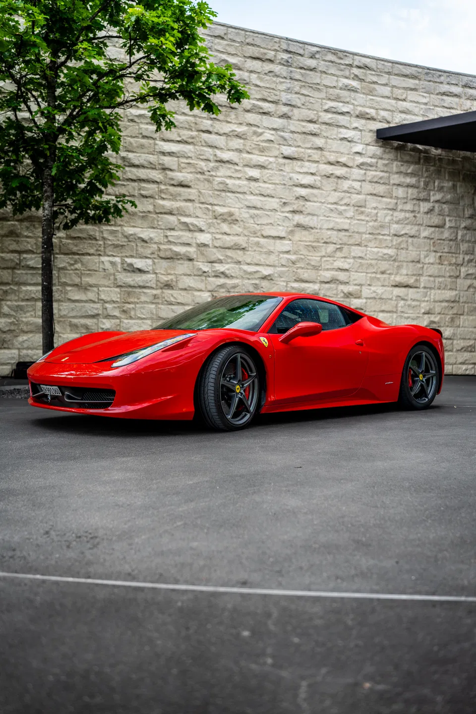 Ferrari 458 Italia beside a stone office façade